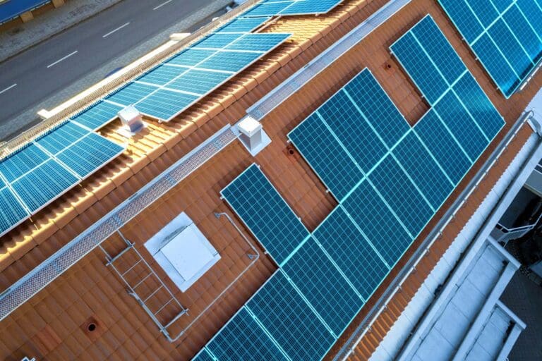 vista-superior-sistema-paneles-fotovoltaicos-solares-azules-azotea-edificio-apartamentos-produccion-ecologica-renovable-energia-verde-scaled